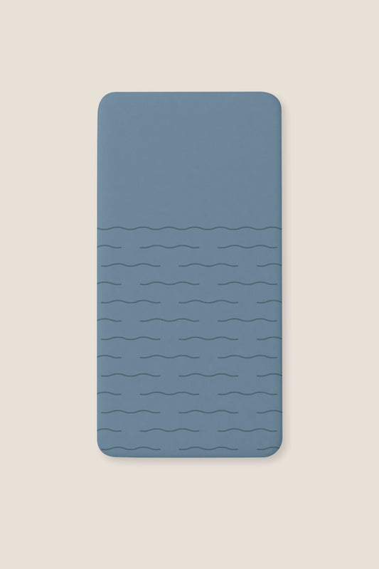 A fitted blue sheet with a subtle wavy horizontal line pattern, shown flat against a light beige background.