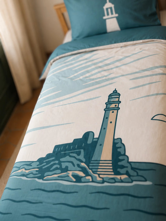 A close-up of a bed featuring the FastNet Rock lighthouse illustration on a duvet cover, with a matching pillowcase.
