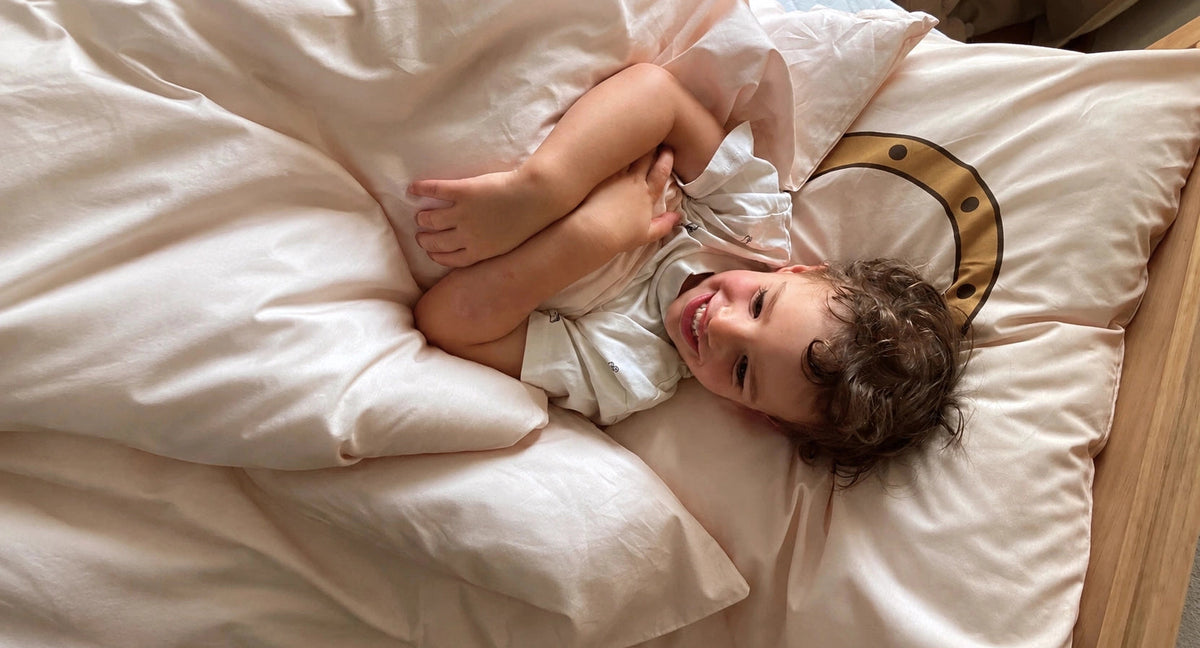 Toddler lying in cosy bed with beautiful nautical soft organic cotton duvet cover.