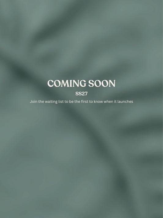 A muted sage green fabric texture background with centered white text reading 'COMING SOON', 'SS27', and smaller text below inviting subscribers to join the waiting list.